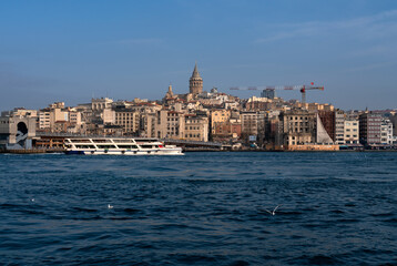 Fototapeta na wymiar View of Beyoglu district with Galata Tower and Galata Bridge in the foreground from the waters of the Golden Horn Bay on a sunny day, Istanbul, Turkey