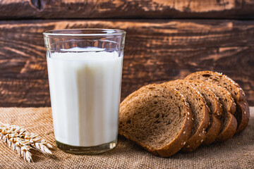 A glass with milk and bread on the table