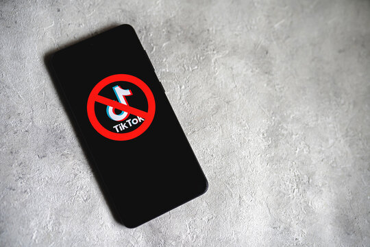 TikTok app logo crossed out with red Ban sign displayed on phone screen. Tik Tok banned in the US concept. Concrete background with copy space. Swansea, UK - February 15, 2023.
