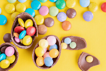 Fototapeta na wymiar Easter concept. Chocolate eggs on yellow background, space for text. Top view