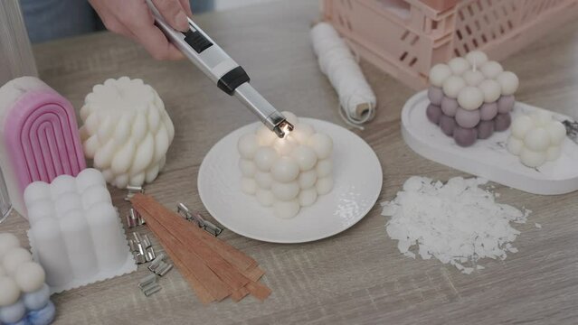 Close up of female hand burning up bauble candle with lighter 