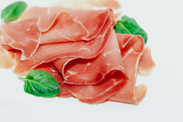 Pieces of dried pork jamon prosciutto on a white background.