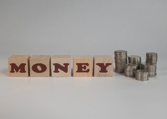 Napis MONEY na drewnianych klockach. Ułożone w słupki monety obok napisu MONEY.