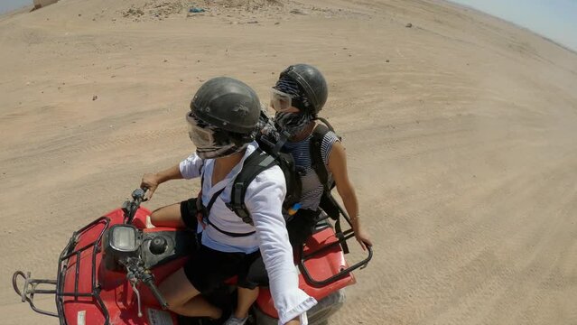 Young copule of tourists having fun speeding on quad bike riding in dunes of Egypt