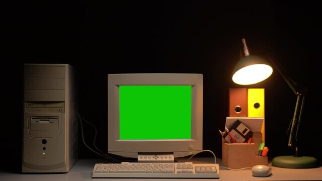 Old computer with green chroma key screen close-up, Desktop PC isolated on black background. Retro obsolete technology.