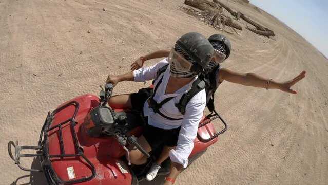 Man and girlfriend with scarfs on their face driving quad bike in the egyptian desert and having adrenaline rush