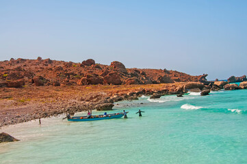 Fishing boats and fishermen locals on the ocean on a sunny hot day on a deserted beach with emerald water. Socotra Island in the Indian Ocean.