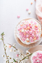 Traditional Easter sweet bread or cakes with white icing and sugar decor, colored eggs and cherry blossom tree branch over white table. Various Spring Easter cakes. Happy Easter day. Selective focus.