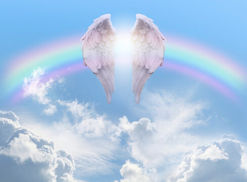 Angel Wings Rainbow Blue Sky Background - pair of angel wings infront of a rainbow arc against a beautiful blue sky with fluffy clouds ideal for a spiritual or religious blessing theme
