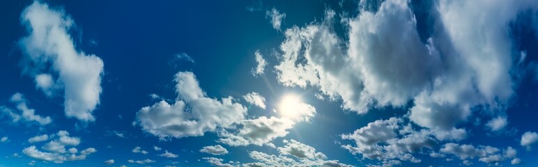 blue sky with perfect clouds and partially sun reflection. The sun shines bright in the daytime in...