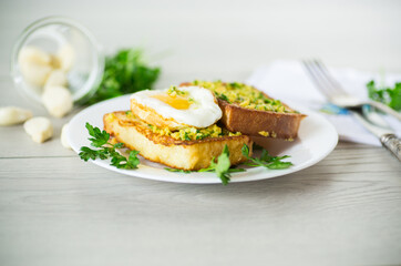 Fried croutons in batter with garlic and herbs and a fried egg in a plate.