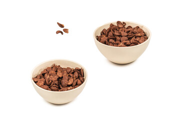 Chocolate corn flakes falling to the white bowl isolated on white. Motion.