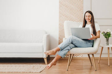 Online shopping at home concept. girl sitting in a chair and looking at a laptop monitor, lifestyle...