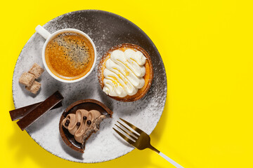 Morning coffee, delicious cake and chocolate on plate. Lunch at work. Copy space. Top view. Yellow background