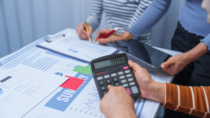 Using calculator, small business accounting team meeting three asian people with salary monthly charts data, basic business accounting and bookkeeping concept.