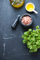 Baby beetroot leaves, pink salt and olive oil on a black marble background, vertical shot with copy space, elevated view
