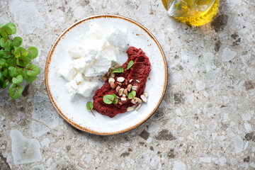 White plate with caviar made of beetroot and feta cheese, flat lay on a brown granite background, horizontal shot with space