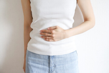 お腹を抑える女性　腹痛イメージ