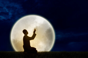 Fototapeta na wymiar silhouette muslim man praying with a huge full moonlight background