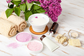 Natural cosmetics with lilac flowers. Set of cream and towel rolls. Face care products. Prepare to bath. Spa therapy concept photo. Organic cosmetic on wooden background. relax and aromaterapy