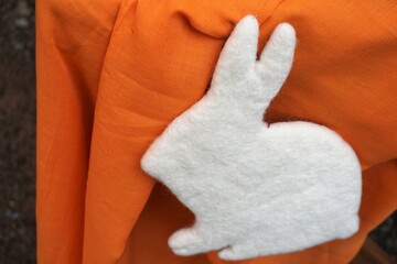 Osterdekoration mit orangener Stofftischdecke mit weißem Osterhasen aus Filz