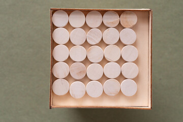 wood circles neatly organized inside a shallow wooden box (photographed on a green background)