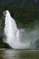 Turbulent waterfall falling from a mountain and striking the peaceful water with wonderful spray