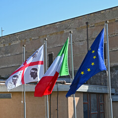 Three flags, flag of the autonomous region Sardinia, Italy and Europe, in the wind 