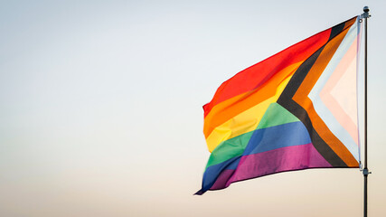LGBT History Month, Pride Month, LGBT Lesbian, Gay, Bisexual, Transgender, Queer or Questioning, Parade Concept. Six-band Rainbow flag waving in wind,  outdoor background, soft focus. Slow motion
