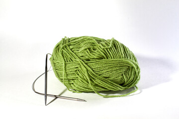 Ball of green wool with metallic spokes on a white background Needlework Concept
