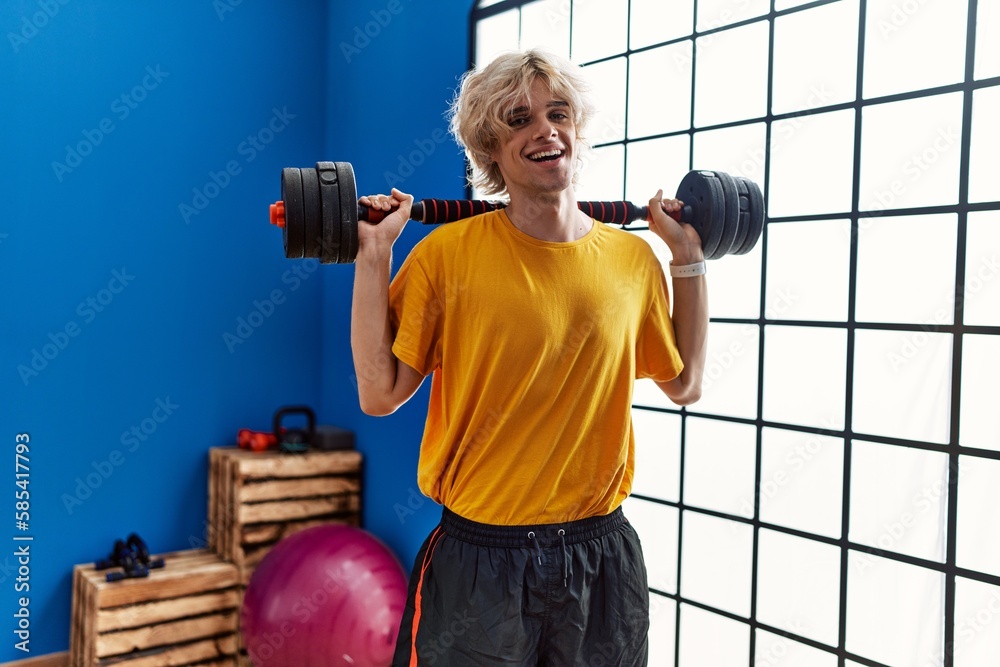 Sticker young blond man smiling confident using weight training at sport center