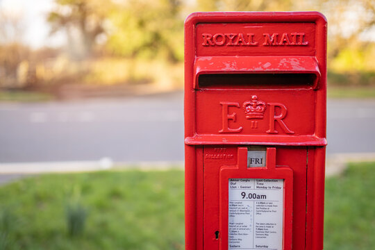 Traditional British red Royal Mail ER mailbox for letters in a Street in Wales, United Kingdom. SWANSEA, WALES, UK - FEBRUARY 25, 2021