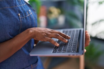 African american woman florist using laptop at florist store