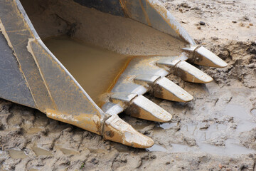 Metal excavator bucket background. Construction site sandy ground. House building background. Heavy...