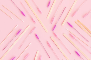 Mascara brushes, tools, wooden sticks isolated on pink background. Makeup pink brushes, makeup kits. Disposable brush for eyelashes and eyebrows. Close-up. Flat lay