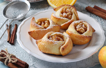 Obraz na płótnie Canvas Buns with apples and cinnamon in the form of roses, sprinkled with powdered sugar