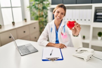 Young hispanic woman wearing doctor uniform wearing gloves at clinic