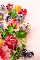 Frozen ice cubes with various berries, blackberries and raspberries, gooseberries and currants, blueberries and mint