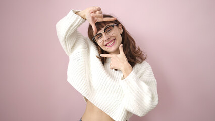 Fototapeta premium Young caucasian woman smiling doing frame shape with hands over isolated pink background