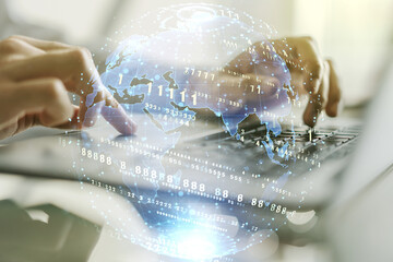 Double exposure of abstract programming language hologram with world map and hands typing on laptop on background, research and development concept