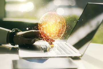 Creative light bulb illustration with hands typing on computer keyboard on background, future...
