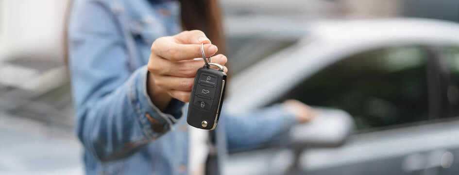 transportation rental automotive business concept. Close up hands of rental auto agent giving car remote key to client to travel sightseeing.