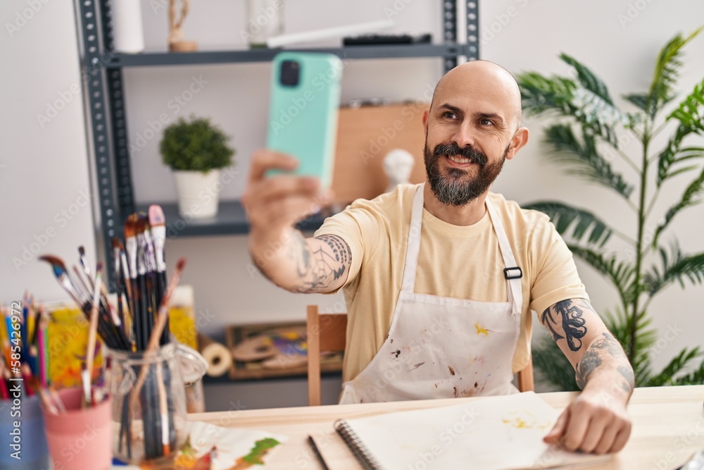 Poster Young bald man artist smiling confident make selfie by smartphone at art studio