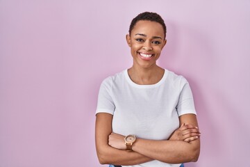 Obraz premium Beautiful african american woman standing over pink background happy face smiling with crossed arms looking at the camera. positive person.