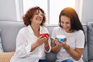 Two women mother and daughter drinking coffee at home