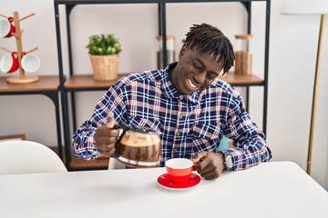 African american man pouring coffee on cup sitting on table at home