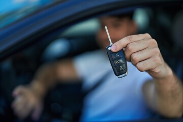 Obraz premium Young hispanic man smiling confident holding key of new car at street