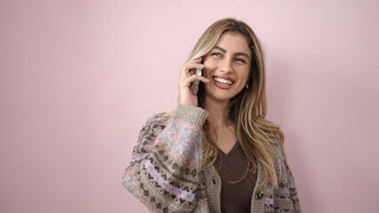 Young blonde woman smiling confident talking on smartphone over isolated pink background