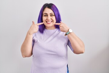 Obraz na płótnie Canvas Plus size woman wit purple hair standing over isolated background smiling cheerful showing and pointing with fingers teeth and mouth. dental health concept.