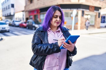 Young beautiful plus size woman smiling confident writing on touchpad at street